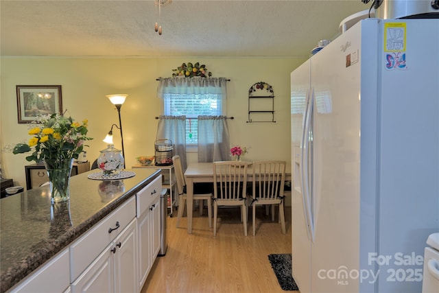 252 Chuckwood Rd, Mooresville, NC 28117 - kitchen with white refrigerator with ice dispenser, light wood-style flooring, white cabinets, a textured ceiling, and dark stone counters