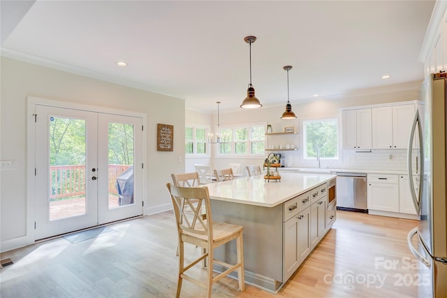 1062 Willow Ridge Ln, Fort Mill, SC 29707 - kitchen featuring stainless steel appliances, light wood-style flooring, a kitchen breakfast bar, backsplash, and ornamental molding