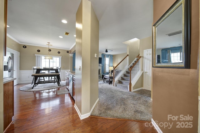 920 Old Forester Ln, Charlotte, NC 28214 - corridor with stairway, dark wood finished floors, ornamental molding, a chandelier, and a wainscoted wall