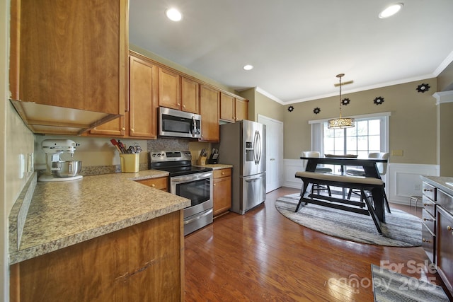 920 Old Forester Ln, Charlotte, NC 28214 - kitchen featuring stainless steel appliances, brown cabinets, ornamental molding, light countertops, and hanging light fixtures