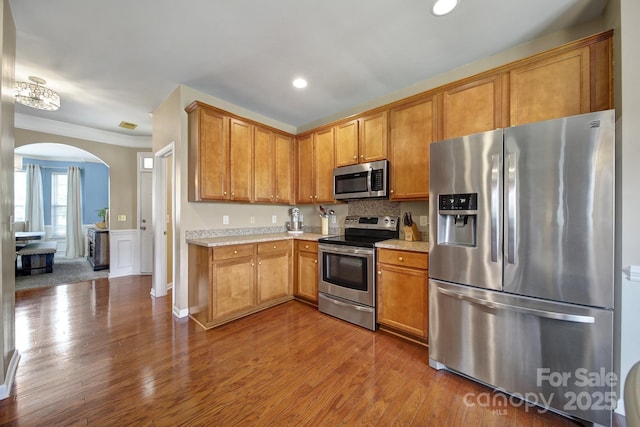 920 Old Forester Ln, Charlotte, NC 28214 - kitchen featuring appliances with stainless steel finishes, arched walkways, light countertops, dark wood finished floors, and crown molding