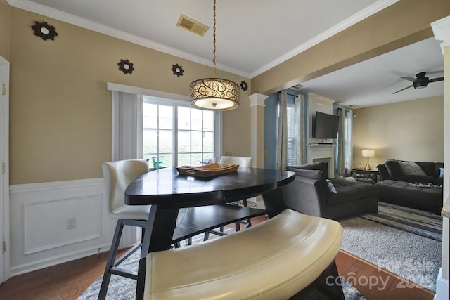 920 Old Forester Ln, Charlotte, NC 28214 - dining space featuring dark wood-style flooring, a ceiling fan, ornamental molding, a fireplace, and a wainscoted wall