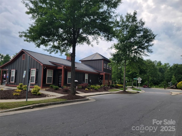 920 Old Forester Ln, Charlotte, NC 28214 - view of front of home featuring board and batten siding, metal roof, and a chimney