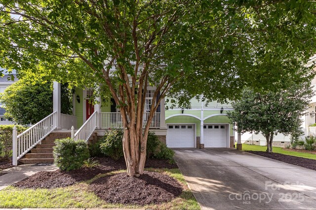 9210 Ginhouse Ln, Charlotte, NC 28277 - obstructed view of property featuring a garage, a porch, concrete driveway, and stairway