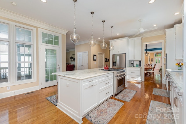 9210 Ginhouse Ln, Charlotte, NC 28277 - kitchen featuring appliances with stainless steel finishes, light wood-type flooring, white cabinets, a center island, and ornamental molding
