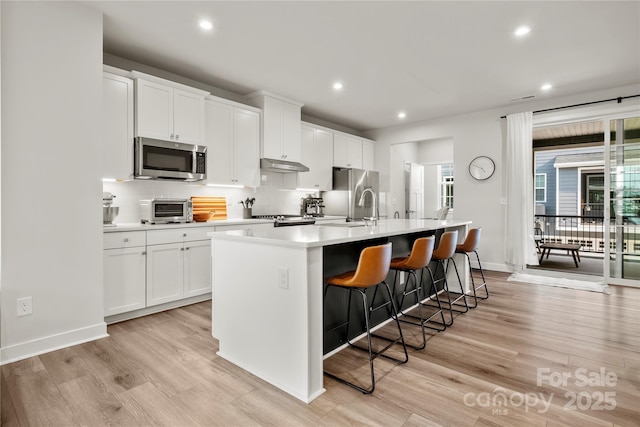 120 August Ln, Stallings, NC 28104 - kitchen featuring appliances with stainless steel finishes, a kitchen island with sink, recessed lighting, light wood-type flooring, and a breakfast bar area