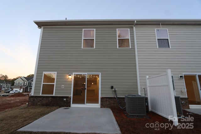 222 Harpers Run Ln, Matthews, NC 28104 - back of property at dusk featuring cooling unit, a patio area, and brick siding