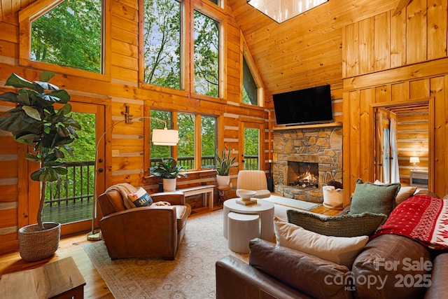 2255 Wolf Laurel Rd, Mars Hill, NC 28754 - living area featuring high vaulted ceiling, plenty of natural light, wooden walls, wood finished floors, and a stone fireplace