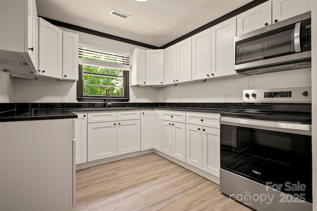 1214 Northwoods Dr, Kings Mountain, NC 28086 - kitchen with appliances with stainless steel finishes, a sink, white cabinetry, light wood-type flooring, and a textured ceiling