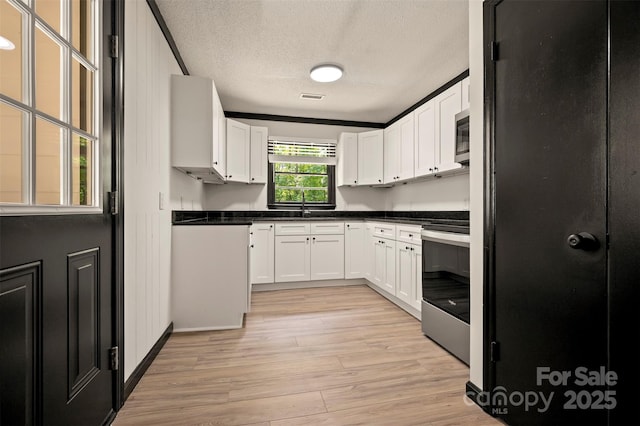 1214 Northwoods Dr, Kings Mountain, NC 28086 - kitchen featuring stainless steel appliances, light wood-style flooring, white cabinets, a textured ceiling, and dark countertops