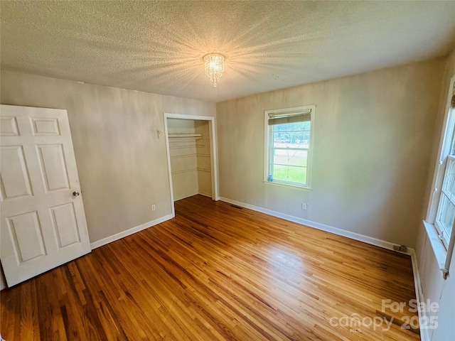 316 Meadowood Cir, Kannapolis, NC 28081 - unfurnished bedroom with wood finished floors, a textured ceiling, a closet, and baseboards