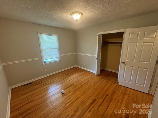316 Meadowood Cir, Kannapolis, NC 28081 - unfurnished bedroom with a textured ceiling, light wood-style floors, a closet, and baseboards