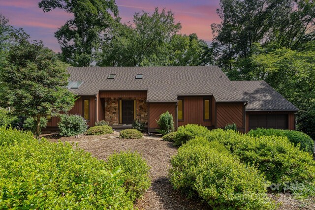 1601 Wandering Way Dr, Charlotte, NC 28226 - mid-century inspired home with a garage, roof with shingles, stone siding, and view of wooded area