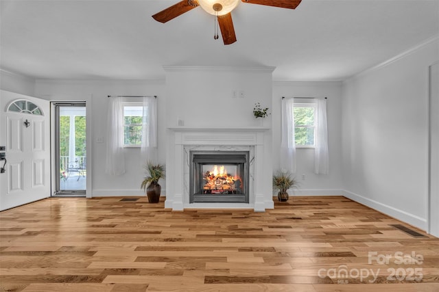 3804 Lippard Ln, Valdese, NC 28690 - unfurnished living room featuring light wood-style flooring, ceiling fan, crown molding, a premium fireplace, and baseboards