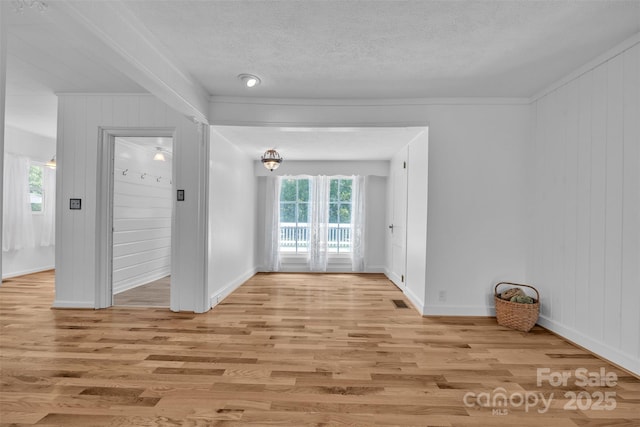 3804 Lippard Ln, Valdese, NC 28690 - empty room featuring light wood finished floors, baseboards, a textured ceiling, crown molding, and wooden walls
