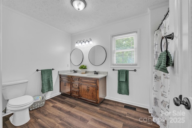 3804 Lippard Ln, Valdese, NC 28690 - bathroom with double vanity, crown molding, a textured ceiling, wood finished floors, and toilet