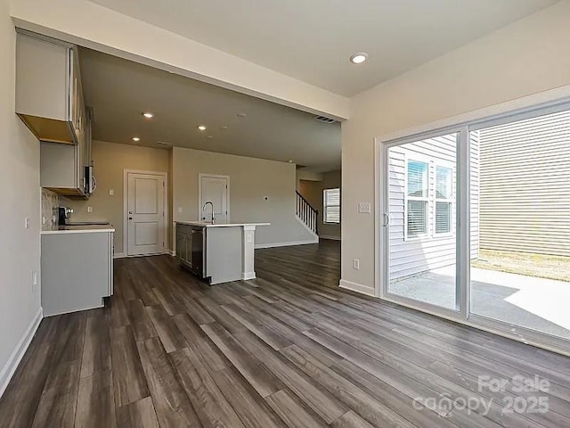 213 Jp Dr, Albemarle, NC 28001 - unfurnished living room featuring dark wood-type flooring, baseboards, stairs, a sink, and recessed lighting
