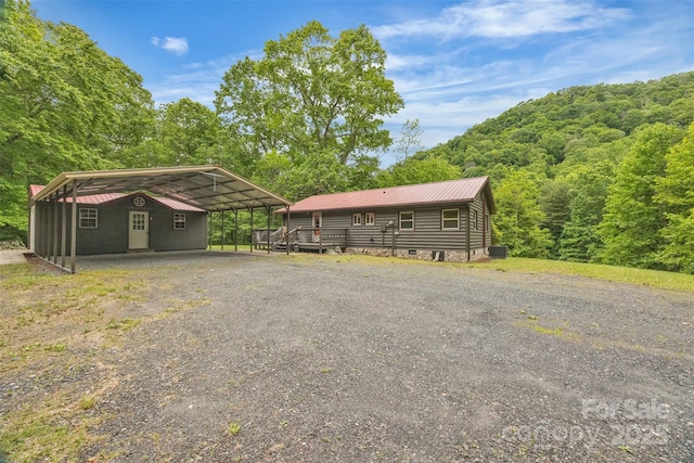 1598 Claybank Rd, West Jefferson, NC 28694 - view of front of house with a detached carport, metal roof, gravel driveway, a view of trees, and central AC