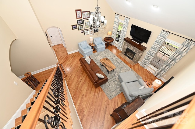 6302 Dwayne Starnes Dr, Hickory, NC 28602 - living area with wood finished floors, a chandelier, arched walkways, a stone fireplace, and baseboards