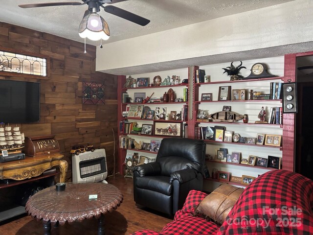 76 Six Springs Rd, Spruce Pine, NC 28777 - living room with wood walls, wood finished floors, a textured ceiling, ceiling fan, and heating unit