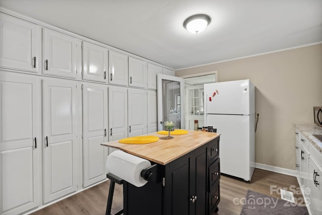 1425 3rd Street Pl NE, Hickory, NC 28601 - kitchen with freestanding refrigerator, dark cabinetry, white cabinets, wood finished floors, and butcher block countertops