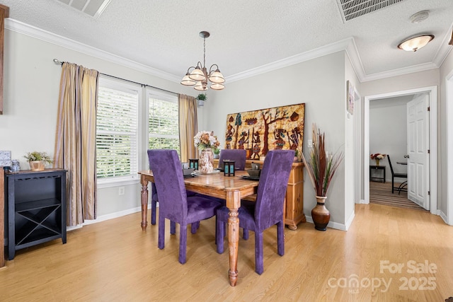 118 Grain Dr, Stony Point, NC 28678 - dining space with light wood-style floors, a chandelier, a textured ceiling, and ornamental molding