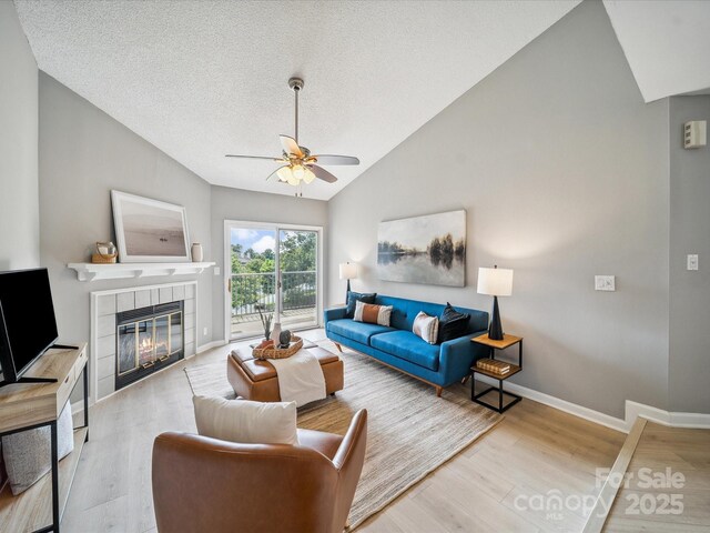 18817 Nautical Dr Unit 302, Cornelius, NC 28031 - living room with ceiling fan, lofted ceiling, a tile fireplace, a textured ceiling, and wood finished floors