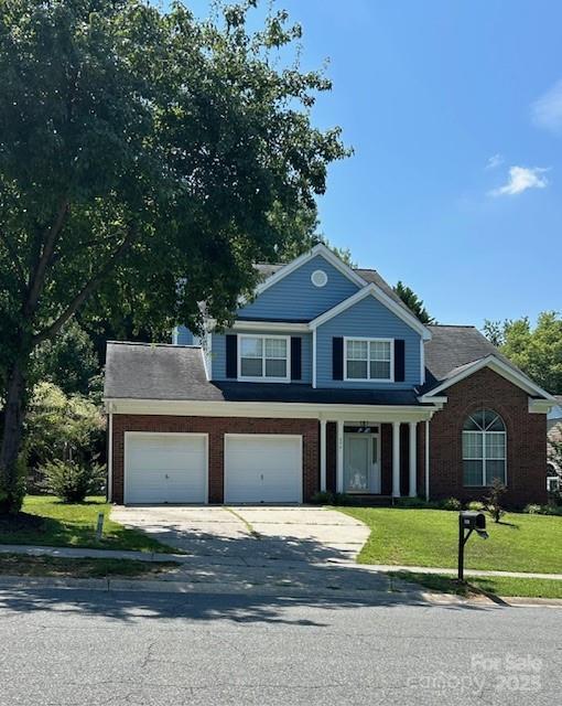 8901 Clifton Meadow Dr, Matthews, NC 28105 - traditional-style house featuring driveway, a front lawn, brick siding, an attached garage, and a porch