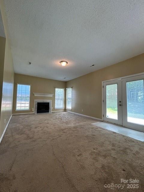 8901 Clifton Meadow Dr, Matthews, NC 28105 - unfurnished living room with carpet flooring, a textured ceiling, french doors, and a premium fireplace