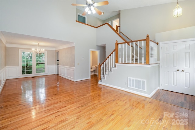 7114 Kinsmore Ln, Charlotte, NC 28269 - unfurnished living room featuring a chandelier, a towering ceiling, stairway, a ceiling fan, and wood finished floors