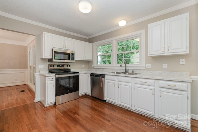 7114 Kinsmore Ln, Charlotte, NC 28269 - kitchen featuring stainless steel appliances, a sink, dark wood finished floors, crown molding, and wainscoting