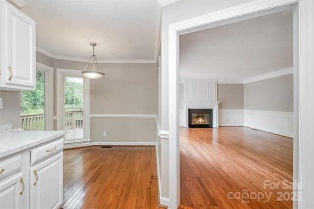 7114 Kinsmore Ln, Charlotte, NC 28269 - kitchen featuring light wood finished floors, white cabinetry, light countertops, a fireplace, and crown molding