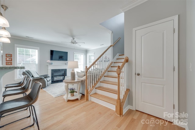14727 Brannock Hills Dr, Charlotte, NC 28278 - staircase featuring a glass covered fireplace, ornamental molding, wood finished floors, a ceiling fan, and plenty of natural light