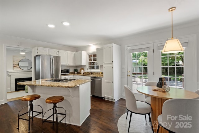 6938 Wrentree Dr, Charlotte, NC 28210 - kitchen featuring appliances with stainless steel finishes, ornamental molding, a center island, white cabinetry, and dark wood finished floors