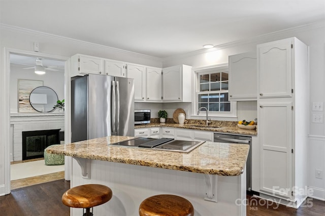 6938 Wrentree Dr, Charlotte, NC 28210 - kitchen featuring appliances with stainless steel finishes, a sink, white cabinets, dark wood-style floors, and a kitchen bar