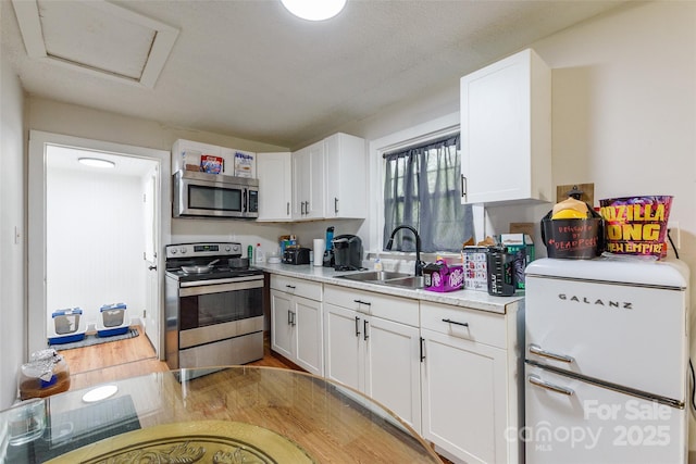 515 Myrtle Ave, Chester, SC 29706 - kitchen featuring appliances with stainless steel finishes, a sink, light countertops, white cabinetry, and light wood-type flooring