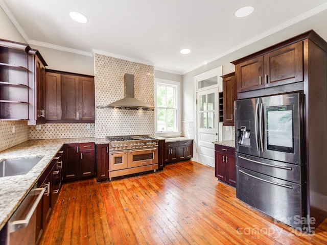 128 W End St, Chester, SC 29706 - kitchen with appliances with stainless steel finishes, wall chimney range hood, hardwood / wood-style floors, decorative backsplash, and light stone counters