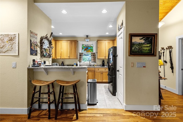 172 Juneberry Ln, Tuckasegee, NC 28783 - kitchen featuring freestanding refrigerator, a peninsula, a kitchen bar, a sink, and baseboards