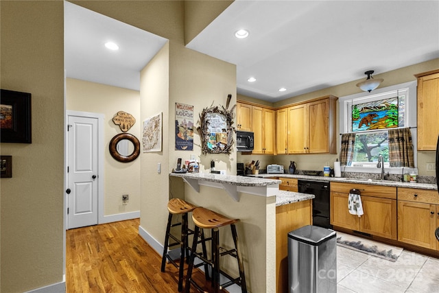 172 Juneberry Ln, Tuckasegee, NC 28783 - kitchen featuring black appliances, a breakfast bar area, light stone countertops, baseboards, and a peninsula