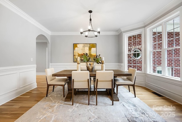 3324 Greenhurst Dr, Weddington, NC 28104 - dining space with light wood finished floors, crown molding, arched walkways, a chandelier, and wainscoting