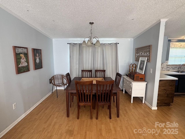 13211 Asbury Chapel Rd, Huntersville, NC 28078 - dining area featuring a chandelier, light wood-style floors, a textured ceiling, crown molding, and baseboards