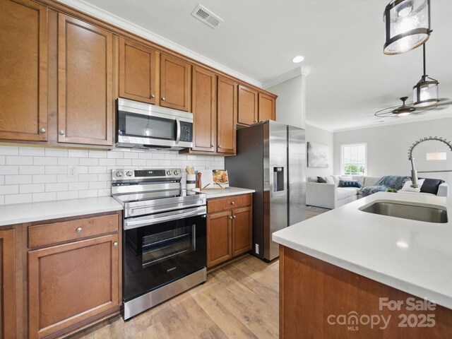 8304 Prescott Glen Pkwy, Waxhaw, NC 28173 - kitchen featuring appliances with stainless steel finishes, brown cabinetry, ceiling fan, ornamental molding, and light wood finished floors