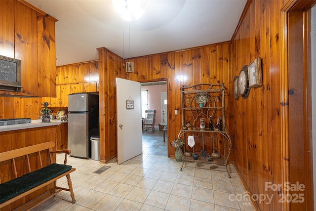 100 S Rudisill Ave, Cherryville, NC 28021 - kitchen featuring freestanding refrigerator, brown cabinetry, wooden walls, light tile patterned floors, and light countertops