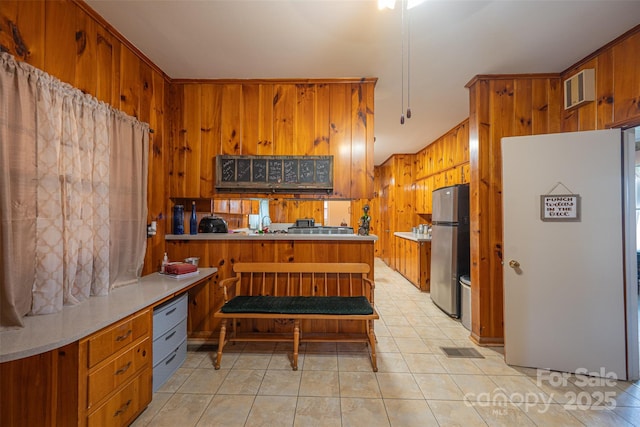 100 S Rudisill Ave, Cherryville, NC 28021 - kitchen featuring freestanding refrigerator, brown cabinets, wooden walls, light tile patterned floors, and light countertops