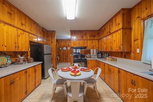 100 S Rudisill Ave, Cherryville, NC 28021 - kitchen featuring electric range, freestanding refrigerator, brown cabinets, wood walls, and light countertops