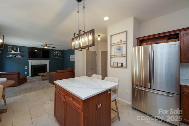2908 Barnard Castle Ln, Matthews, NC 28104 - kitchen with freestanding refrigerator, ceiling fan, a kitchen bar, a fireplace, and hanging light fixtures