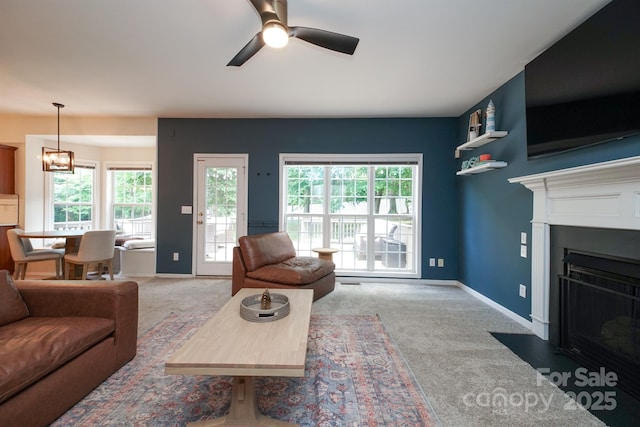 2908 Barnard Castle Ln, Matthews, NC 28104 - carpeted living area featuring ceiling fan, a fireplace with flush hearth, baseboards, and a chandelier