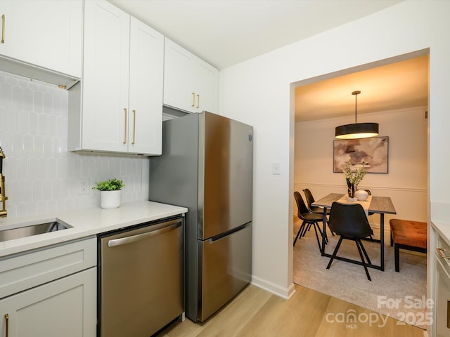 4754 Hedgemore Dr Unit E, Charlotte, NC 28209 - kitchen with stainless steel appliances, light wood-style floors, light countertops, tasteful backsplash, and decorative light fixtures