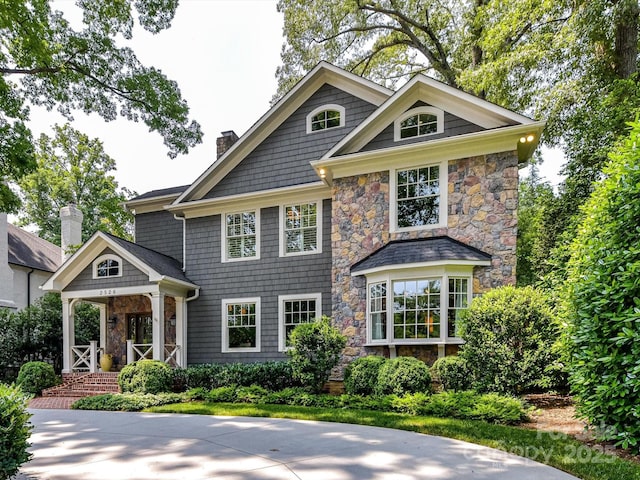 2526 Sherwood Ave, Charlotte, NC 28207 - shingle-style home featuring stone siding, a chimney, and a porch