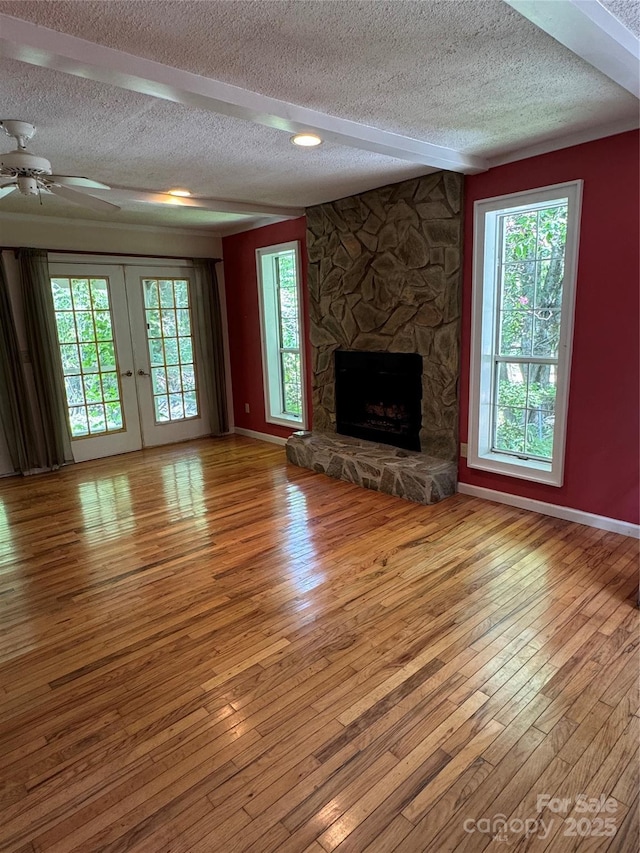 232 Cole Hollow Rd, Newland, NC 28657 - unfurnished living room with a textured ceiling, wood finished floors, a fireplace, a ceiling fan, and french doors